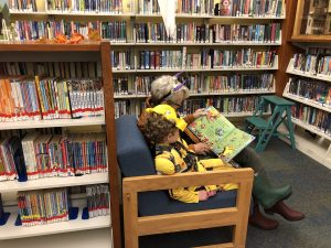 child & woman in costumes reading