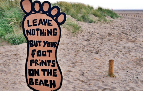 Leave Nothing But Your Footprints sign on beach