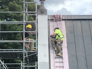 Workers working on the coping stones along the edge of the roof.