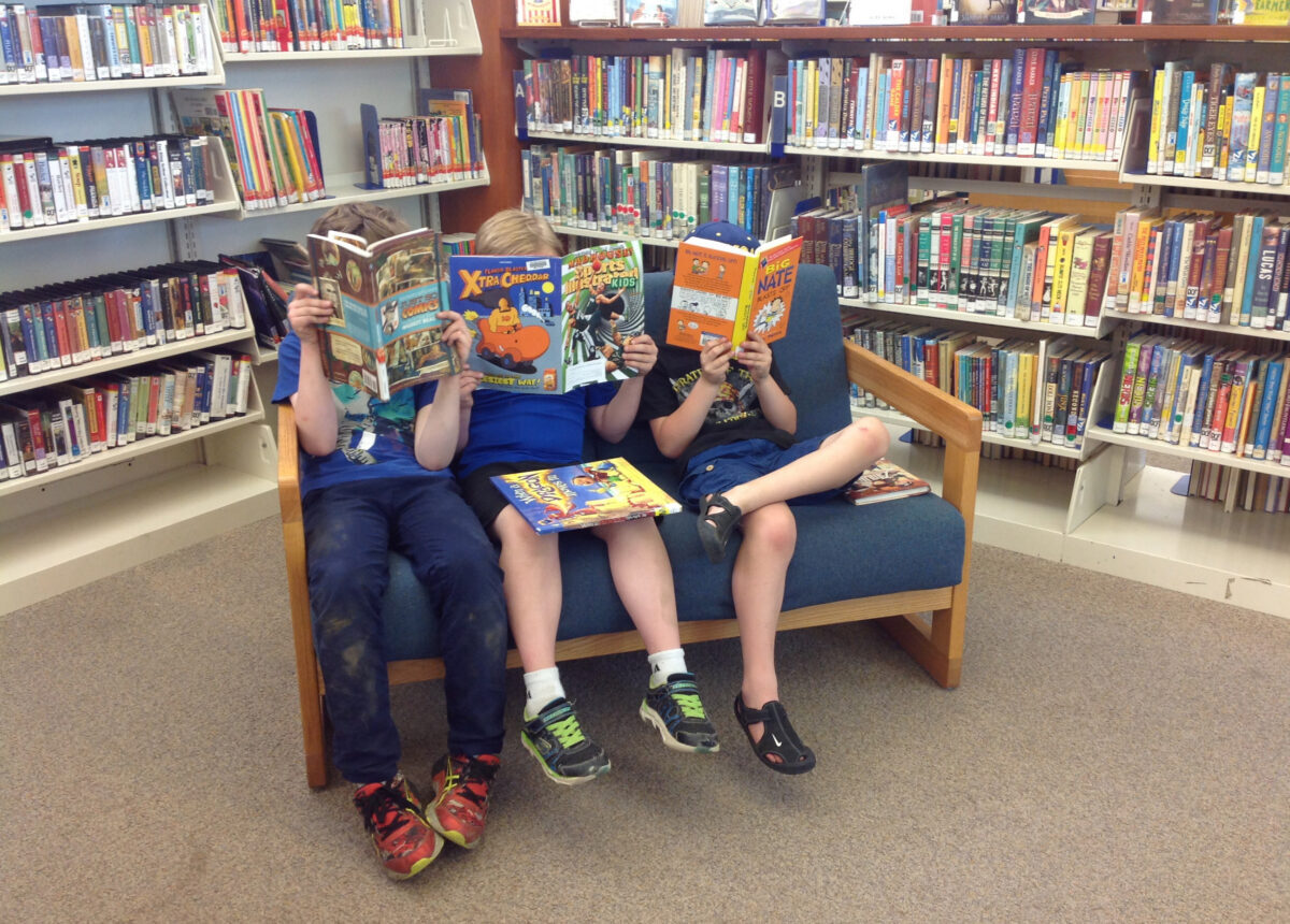 Three kids reading in the Norman Williams Children's Room