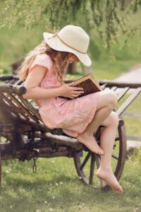 girl in hat reading outdoors
