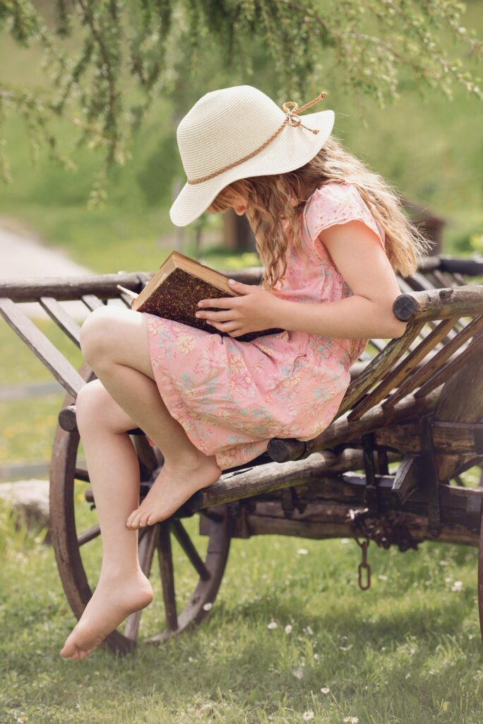 girl in hat reading outdoors